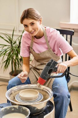 Bir zanaatkar, canlı sanat malzemeleriyle çevrili çanak çömlek çarkında bir kase şekillendirir..