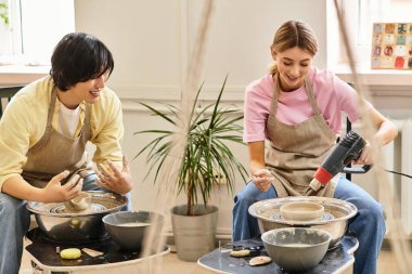 Genç bir çift kil ve yaratıcılıkla dolu canlı bir stüdyoda neşeli bir çömlek yapıyor..