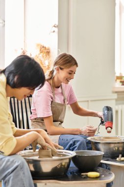 Genç bir çift çömlek atölyesinde birlikte kil şekillendiriyor, bağlantılarını kucaklıyor..