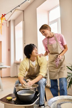 Bir çift, parlak ve rahat bir stüdyo ortamında kilden çömleğe dönüşürken eğleniyor..