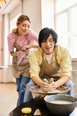 Parlak bir stüdyoda aşklarını sergileyen bir çift birlikte çömlek yapıyorlar..