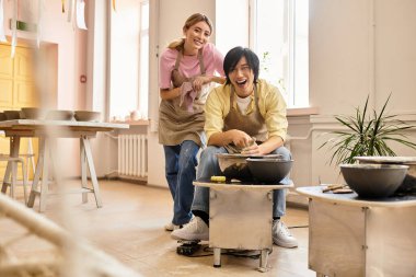Neşeli bir çift çamuru şekillendirir ve güneşli bir çömlek stüdyosunda kahkahaları paylaşır..