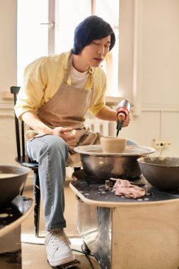 Odaklanmış sanatçı, kilden eşsiz çömlek parçaları oluşturuyor. Parlak, hoş bir stüdyo alanı..