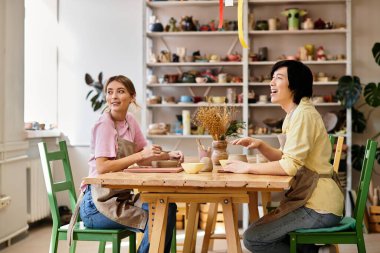 Erkek ve kadın eğlenceli bir çömlek seansının keyfini çıkarıyorlar, canlı bir stüdyoda gülüyorlar ve sanat yaratıyorlar..