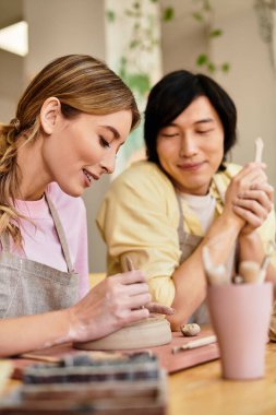 Genç çift birlikte çanak çömlek yapıyor, gülümseme ve aşkla dolu eşsiz parçalar yaratıyorlar..