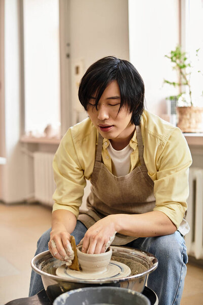 Руки искусно формируют влажную глину в красивую чашу в окружении художественных инструментов.