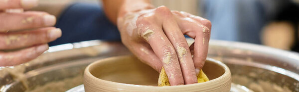 Hands skillfully mold and refine clay in an inviting pottery studio filled with artistic energy