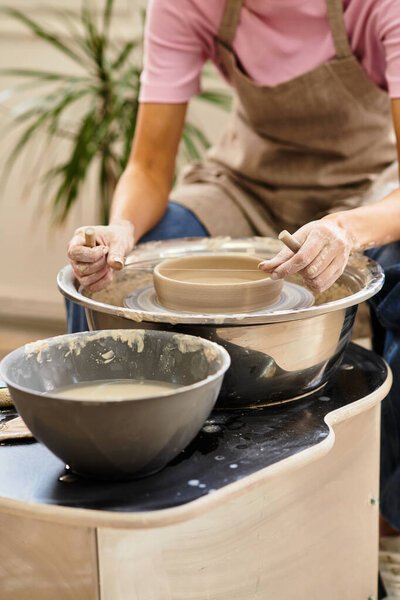 Руки образуют мокрую глину на гончарных кругах среди художественных инструментов и материалов.
