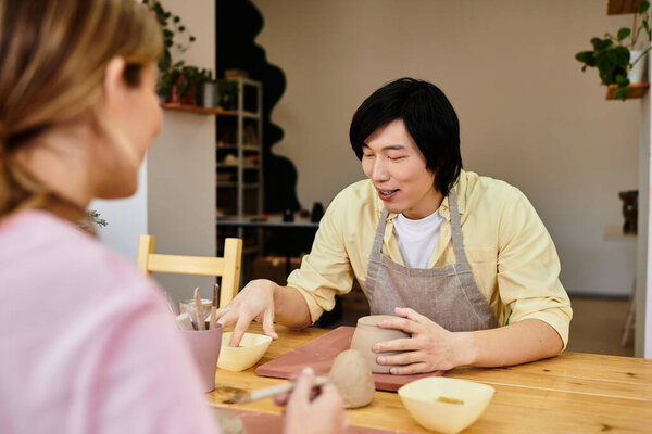 Молодая пара занимается керамикой, делится улыбками и творчеством в уютной студии.