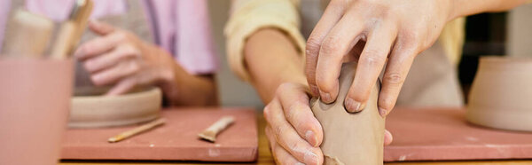 Two individuals share a moment of joy as they sculpt clay together at a pottery studio.