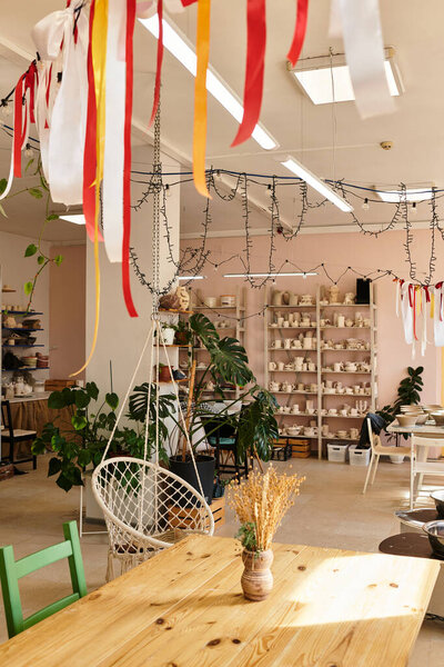 Vivid clay pots and decorations in a vibrant pottery studio filled with plants.