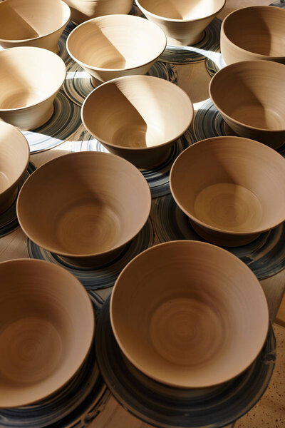 Sunlight shines on pottery bowls awaiting finishing touches in a creative studio.