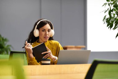 Kulaklık takan genç, zarif bir kadın not alırken dizüstü bilgisayarıyla takılıyor..