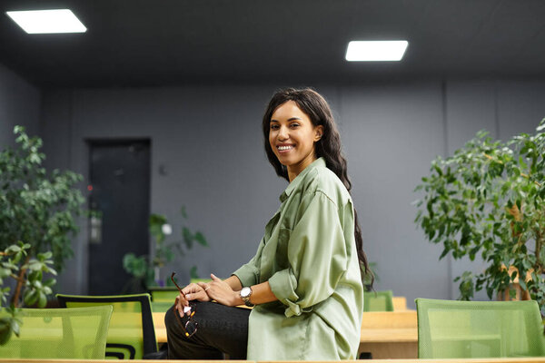 Женщина за работой в стильном офисе в окружении растений и бурной атмосферы.