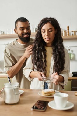 Bir çift, kahvaltılarını hazırlarken davet ettikleri mutfakta sıcak bir anın tadını çıkarıyor..
