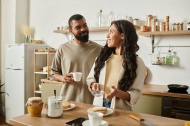 Neşeli çift, sıcak ev mutfağında kahvaltı yaparken tatlı anlar paylaşır..