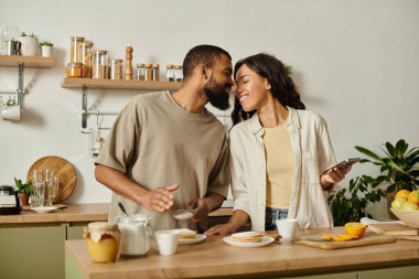 Neşeli bir Afrikalı Amerikalı çift sıcaklıkla dolu sıcak bir mutfakta birbirlerine eşlik etmekten zevk alıyor..