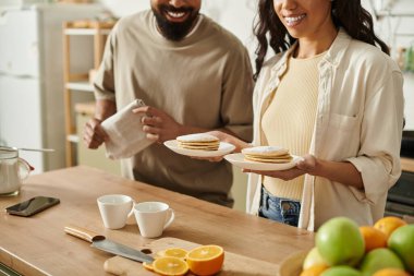 Kahkahalar, kahvaltıyı hazırlarken gözlemeleri neşeyle paylaşan bir çift olarak mutfağı doldurur..