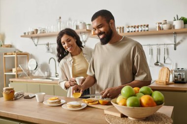 Bir erkek ve bir kadın birlikte kahvaltı hazırlayıp, evlerinde sevgi dolu bir atmosfer yaratıyorlar..