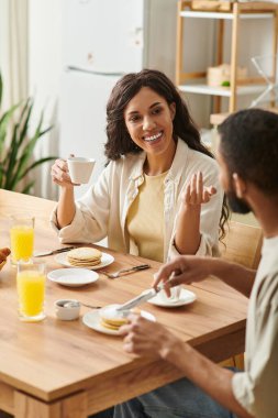 Çiftler, sıcak bir evde kahvaltıda kahkaha ve sohbet ederler..