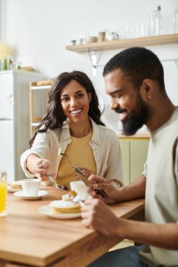 Mutlu bir Afro-Amerikan çifti kahvaltıdan sonra evde krep ve kahkaha yiyor..