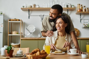 Neşeli bir Afro-Amerikan çifti kahvaltılarının tadını çıkarırken bir yandan da.