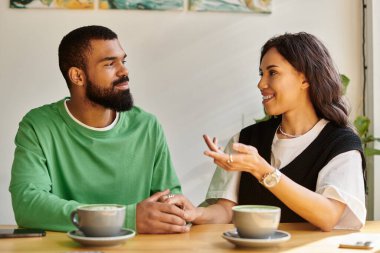 Afro-Amerikalı bir çift, büyüleyici bir kafede sıcak bir kahve eşliğinde sohbet etmekten zevk alır..