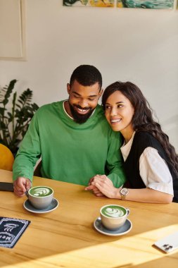 Neşeli bir çift, neşeli bir kafede içkilerini yudumlarken kahkahalar ve sıcaklığı paylaşır..