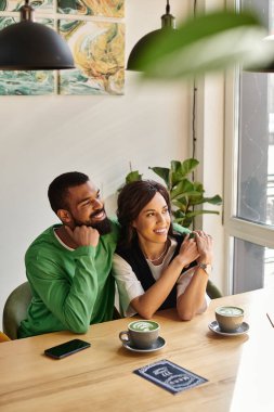 Afro-Amerikalı bir çift, canlı bir kafede birlikte olmaktan zevk alıyor, içkinin tadını çıkarıyor..