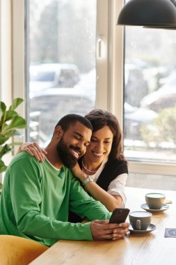 Neşeli bir çift birlikte özel bir anı paylaşır. Parlak bir kafede, gülümseyen ve rahat..