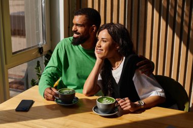 Bir çift birlikte rahatlar, kahvelerini yudumlar ve bir kafede birlikte vakit geçirirler..