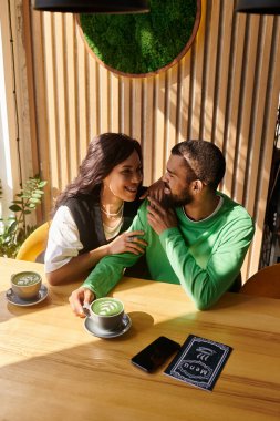 Afro-Amerikalı bir çift kahve eşliğinde kahkaha ve şefkat paylaşıyor..