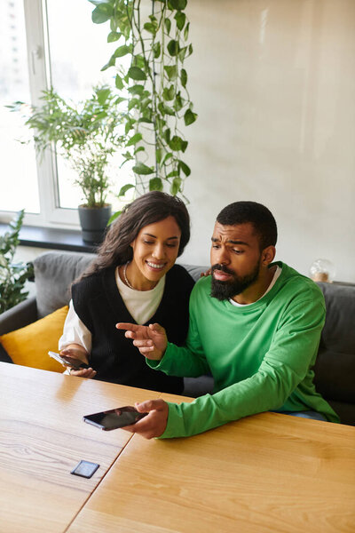 В стильном кафе афроамериканская пара смеется и болтает, разговаривая по телефону..