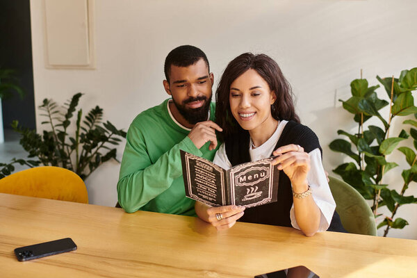 Улыбающаяся пара сидит в кафе, разделяя моменты, когда они вместе читают меню.