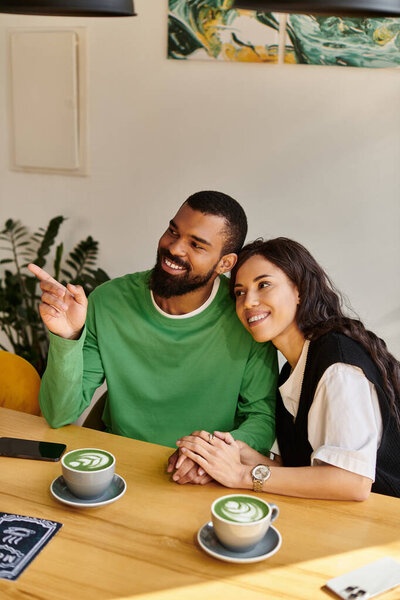 Африканская американская пара сидит близко в очаровательном кафе, делясь улыбками и теплыми напитками.