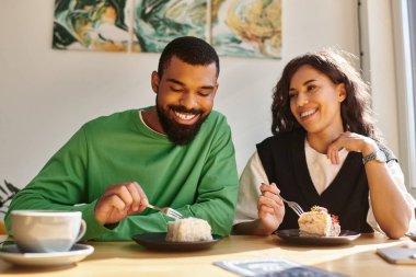 Mutlu bir çift sıcak bir kafe atmosferinde otururken lezzetli tatlılardan zevk alır..