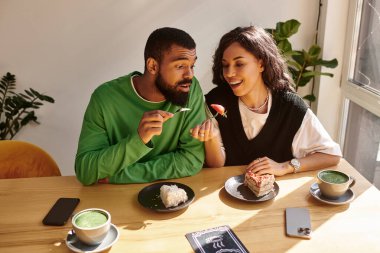 Afro-Amerikalı bir çift gülümseme ve kahkahaları paylaşırken tatlı ve içkinin tadını çıkarıyor..