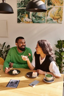 Afro-Amerikalı çift sıcak bir kafe ortamında tatlı ve sohbetin tadını çıkarıyor..