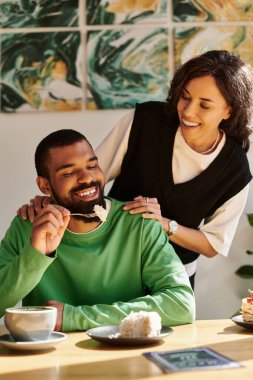 Afro-Amerikalı bir çift canlı bir kafe atmosferinde tatlı bir ziyafetin tadını çıkarıyor..