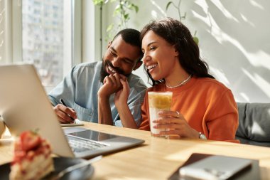 Afrika kökenli Amerikalı bir çift, sıcak bir kafede kahve içerken serbest iş birliği yapıyor..