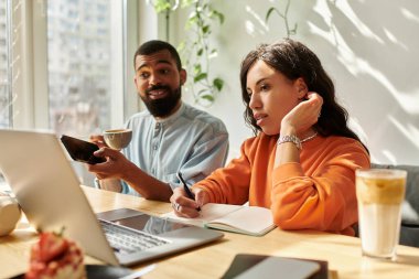 Afrika kökenli Amerikalı bir çift kahvelerini içerken bir kafede uzaktan çalışırlar..