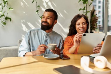 Neşeli bir çift, samimi bir kafede dizüstü bilgisayarlar üzerinde çalışırken fikirlerini paylaşıyor..
