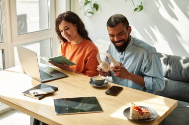 Afrikalı Amerikalı bir çift kafede kahve içerken serbest projelerde işbirliği yapıyor..