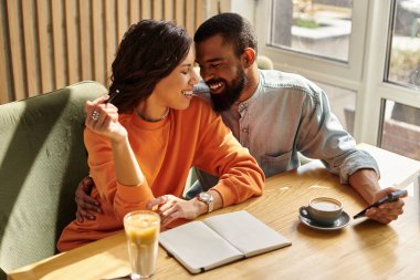 Sevecen bir çift bir kafede birlikte vakit geçirmekten zevk alır, kahkahalar atar ve gülümserler..