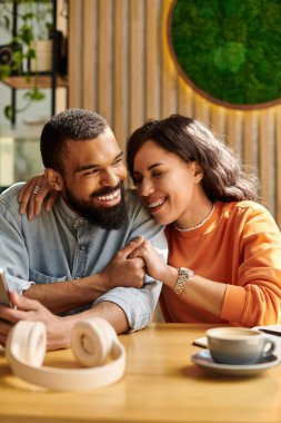 Afro-Amerikalı bir çift, sıcak bir kafede gülüp, hikayeler paylaşmaktan zevk alır..