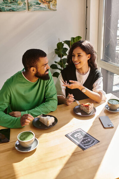 Теплая атмосфера окружает радостную пару, делящую десерт и смех в очаровательном кафе