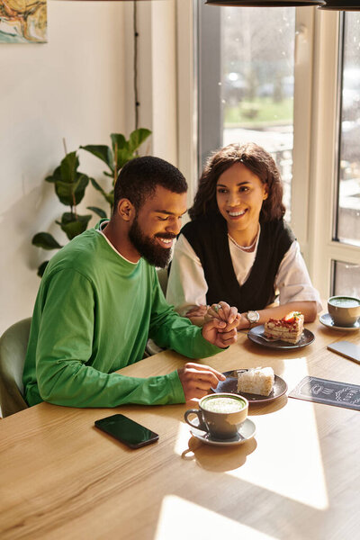 Афро-американская пара проводит радостный момент в кафе, наслаждаясь десертами и напитками.