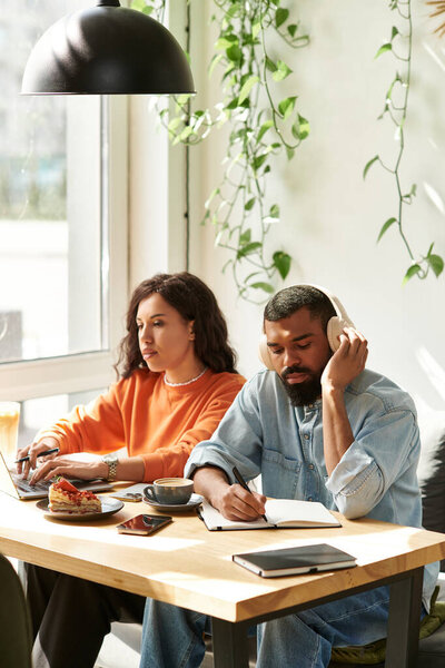 Афро-американская пара работает над внештатными заданиями, наслаждаясь яркой атмосферой кафе.