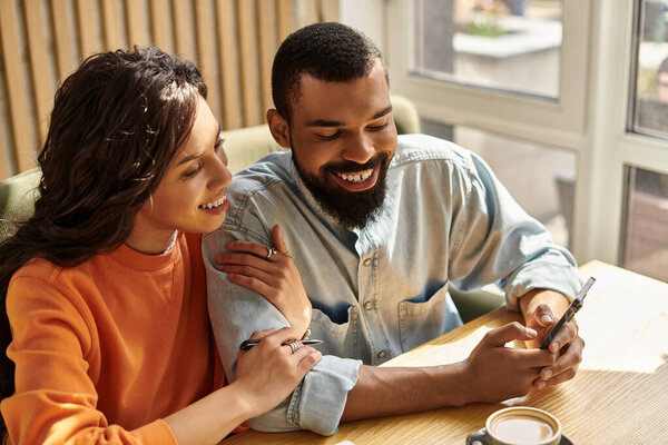 Афро-американская пара весело проводит время в кафе, обмениваясь улыбками и телефоном.
