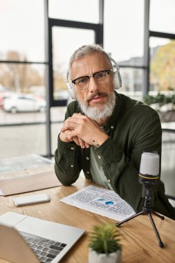 Gözlüklü odaklanmış biri, modern bir masada müzik dinlerken çok çalışır..